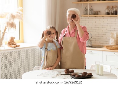 Baking Is Fun. Senior Lady And Her Grandchild With Chocolate Muffins Being Silly In Kitchen, Empty Space