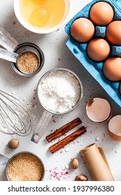 Baking Ingredients And Kitchen Utensils On A White Background Top View. Baking Background. Flour, Eggs, Sugar, Spices, And A Whisk On The Kitchen Table. Flat Lay.