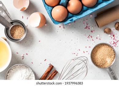 Baking ingredients and kitchen utensils on a white background top view. Baking background. Flour, eggs, sugar, spices, and a whisk on the kitchen table. Flat lay.