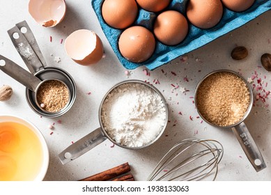 Baking ingredients and kitchen utensils on a white background top view. Baking background. Flour, eggs, sugar, spices, and a whisk on the kitchen table. Flat lay. - Shutterstock ID 1938133063