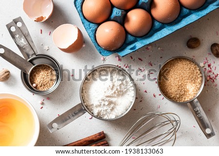 Baking ingredients and kitchen utensils on a white background top view. Baking background. Flour, eggs, sugar, spices, and a whisk on the kitchen table. Flat lay.