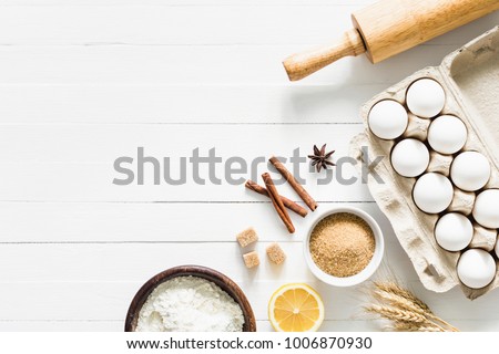 Baking ingredients on white table. White eggs, rolling pin, flour, sugar and spices. Home baking concept, baking cake or cookies ingredients