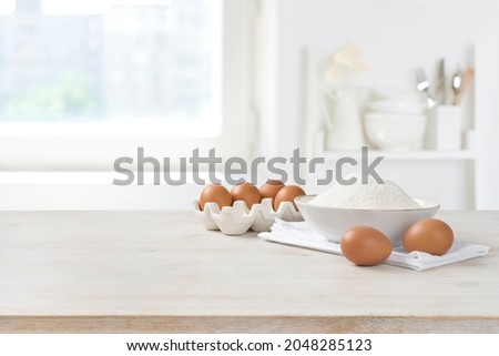 Baking ingredients on wooden table over defocused kitchen window background