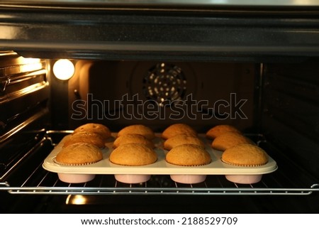 Baking pan with cupcakes in modern oven