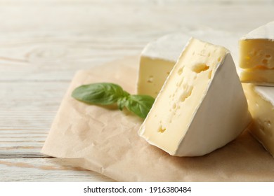 Baking paper with camembert cheese and basil on wooden background