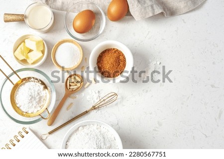 Baking pastry or cake ingredients, brown sugar, butter, flour, eggs and milk with utensil on marble table, top view with copy space