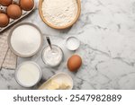 Baking powder and other products on white marble table, flat lay. Space for text