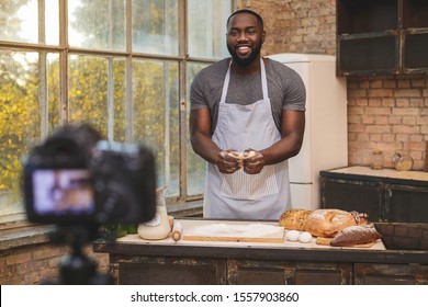 Baking process. Young cooking african man speaker talking on digital camera recording vlog. African male vlogger or shooting blog filming reportage advertising video, coaching.  - Powered by Shutterstock