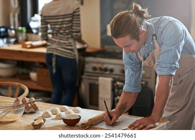 Baking, recipe and writing with man in kitchen of home for cooking, ingredients reminder or planning. Eggs, flour and rolling pin with chef person in apartment for meal or pastry preparation - Powered by Shutterstock