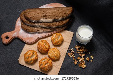 Baking, rolls and bread on a wooden board.
The nuts are scattered. Food photography on a dark background