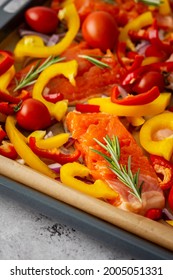 Baking sheet with cooked fish for baking, red fish Arctic char with tomatoes and peppers and rosemary on a baking sheet close-up