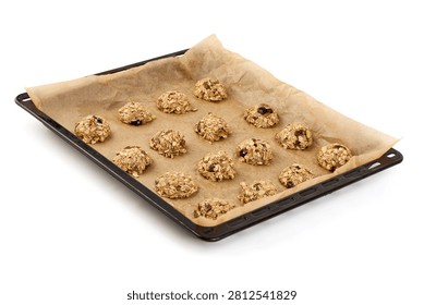 A baking sheet lined with parchment paper holds several unbaked oatmeal cookies, ready for the oven, set against a clean white background.