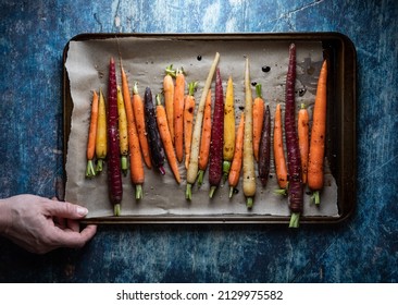 A Baking Sheet With Roasted Rainbow Carrots, Against A Blue Background.