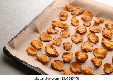 Baking Sheet With Sweet Potato Chips On Grey Background