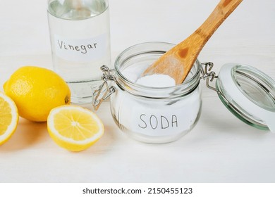 Baking Soda In Jar, Vinegar, Lemon, Wooden Spoon On A White Background. The Concept Of Removing Stains On Clothes. High Quality Photo