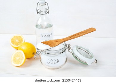 Baking Soda In Jar With A Wooden Spoon On Top, Vinegar, Lemon On A White Background. The Concept Of Removing Stains On Clothes. High Quality Photo