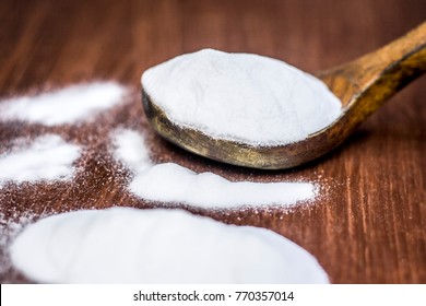 Baking Soda Or Sodium Hydrogen Carbonate In A Wooden Scoop On The Brown Wooden Surface.