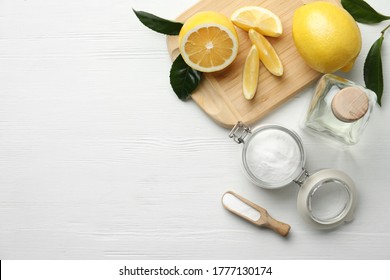 Baking soda, vinegar and cut lemons on white wooden table, flat lay. Space for text