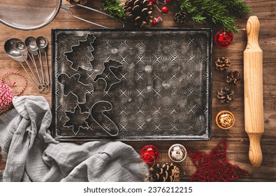 A baking tray with some christmas cookie cutters and copy space, surrounded by christmas decorations. Bakery background.