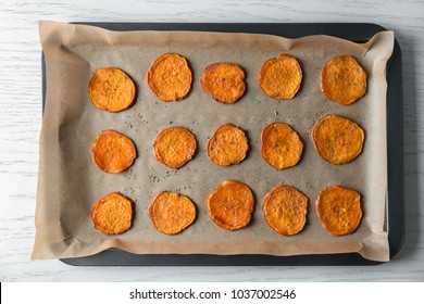 Baking Tray With Tasty Sweet Potato Chips On Wooden Table, Top View