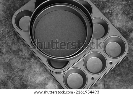 Baking trays and cake tins on a black stone background. Cooking utensils concept