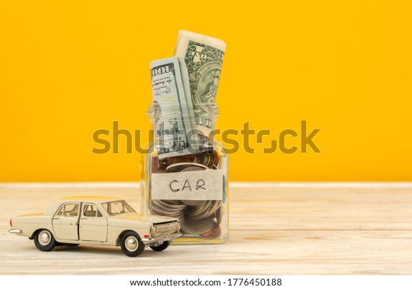 Baku / Azerbaijan - July 9 2020: Savings for car\
in glass jar and small car\
toy