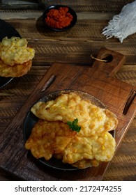 Bakwan Jagung, Corn Fritters With Sambal Merah (red Chili Sauce) Served On A Black Plate With Parsley Leaf. Indonesian Cuisine, Oily.