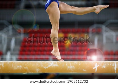 Balance beam artistic gymnastics competition performance. Close up detail of woman athlete feet on air, jump training session exercise at an indoor sport stadium arena. 