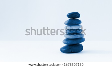 Balance, peace of mind, stones forming a pyramid on a white surface, minimalism, toned classic blue, 2020