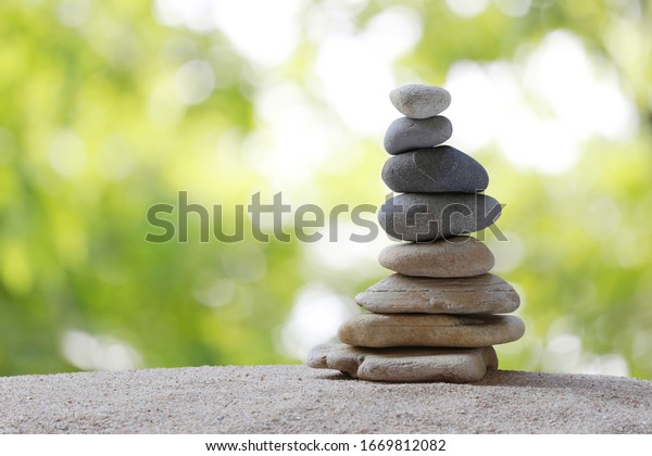 Balance stones are arranged in a\
pyramid shape,Stone Stacked on green nature\
background.