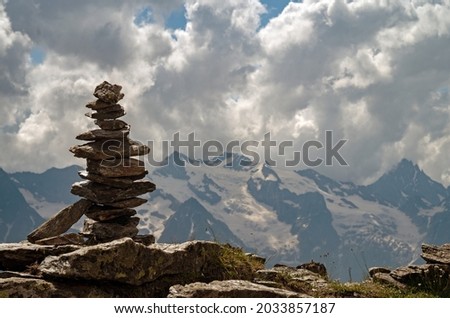 Balance of stones. Balancing stones on the top of boulder. Close up. Balance of stones on a blue sky and mountains background with a copy space. Stones balance, sustainability concept.