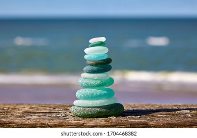 Balance Of Stones. Glass Stones On A Wooden Table Against The Sea