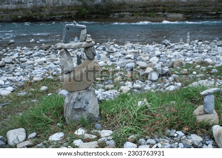 Balance of stones on the river bank, multi-level, gravity, pebbles, stone therapy, art, grass, high, heavy stones, zen, calmness, signs, a way of meditation, relaxation, stable, proportions, nature