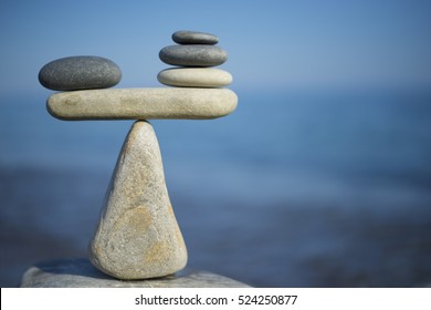 Balance of stones. To weight pros and cons. Balancing stones on the top of boulder. Close up. Balance of stones on a blue sky background with a copy space. Scales. Stones balance, sustainability. - Shutterstock ID 524250877