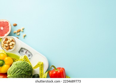 Balanced diet concept. Top view photo of scales vegetables fruits grapefruit sweet pepper almonds cashew and tape measure on isolated pastel blue background with empty space - Powered by Shutterstock