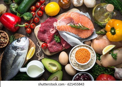 Balanced diet food background. Organic food for healthy nutrition. Ingredients for cooking. Top view over dark stone table.