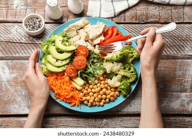 Balanced diet and healthy foods. Woman eating dinner at wooden table, top view - Powered by Shutterstock