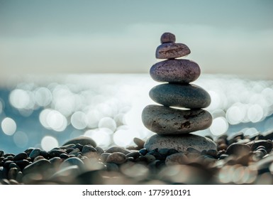 Balanced Pebbles Pyramid on the Beach on Sunny Day and Clear Sky at Sunset. Blue Sea on Background. Selective focus, Bokeh. Zen stones on sea beach, meditation, spa, harmony, calm, balance concept - Powered by Shutterstock