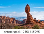 Balanced Rock, a famous landmark of Arches National Park, Utah, USA. Early winter, snow on the mountains in the background. 