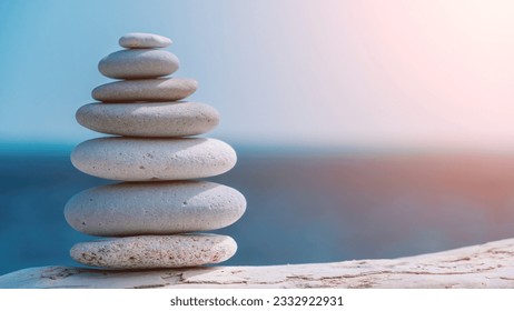 Balanced rock pyramid on sea pebbles beach, sunny day and clear sky at sunset. Golden sea bokeh on background. Selective focus, zen stones on sea beach, meditation, spa, harmony, calm, balance concept - Powered by Shutterstock