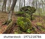 A balanced sandstone boulder stands  on a forested bluff in Indiana.