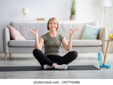 Balanced Senior Woman Sitting In Lotus Pose And Making Gyan Mudra With Her Hands, Meditating On Sports Mat At Home. Peaceful Mature Lady Practicing Yoga And Mindfulness, Copy Space