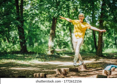 Balancing Exercise Outdoors. Mature Woman Standing On One Leg, Exercising Balance 
