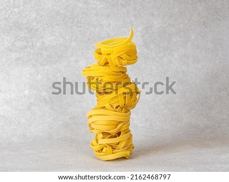 Balancing pasta nests in a stack on light grey background.