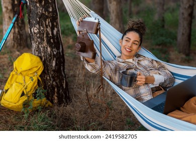 Balancing photography and productivity, the curly-haired freelancer captures a selfie with her camera, her laptop open in her lap. - Powered by Shutterstock