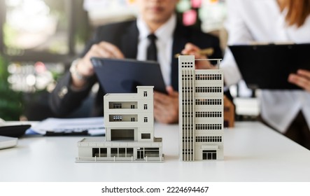balancing the property sector The real estate agent is explaining the house style to see the house design and the purchase agreement.Wooden house at modern office - Shutterstock ID 2224694467