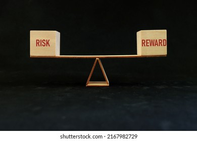 Balancing risk and reward word on seesaw scale in dark black background. Risk-reward ratio business concept.