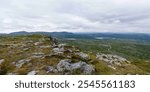 Balancing stones on a green rocky mountain top on a cloudy day in Norway with a beautiful panoramic view