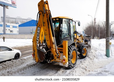 Balashikha, Russia - February 20, 2021. Yellow backhoe loader JCB-3CX clears the snow. Cloudy winter view.