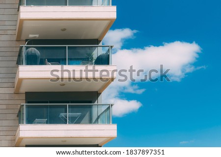 Balconies and blue sky with clouds. Part of a residential building in Israel. Modern apartment buildings on a sunny day. Architectural details. Modern residential white building with balcony 